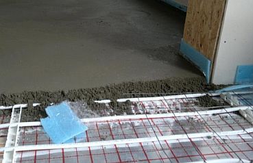 Larawan - Pagbuhos ng kongkretong screed sa underfloor heating pipeline